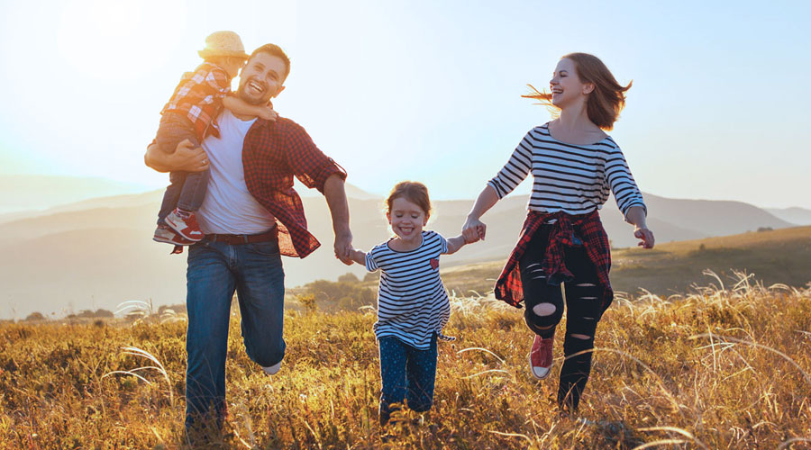 Familie mit Kinder läuft glücklich über eine Wiese