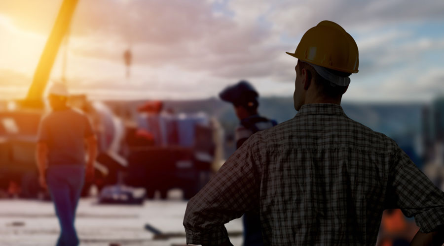 Bauleiter beobachtet eine Grossbaustelle im Sonnenuntergang